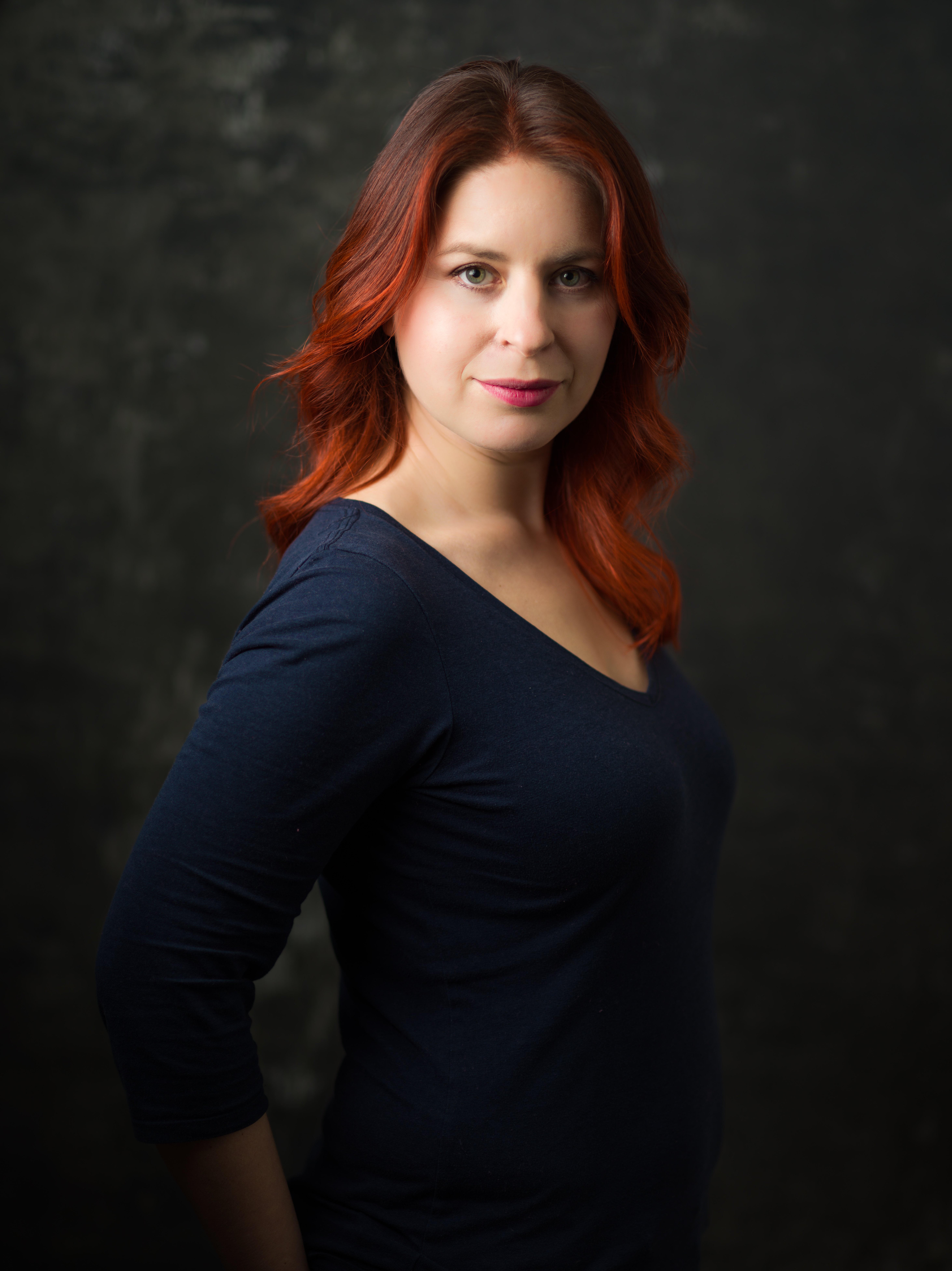 Author portrait photo of Holly Race. Holly is waring a navy blue top and is looking to the camera. She has dark red hair